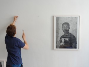ja'n putting a nail in the wall next to a photograph of zanele muholi